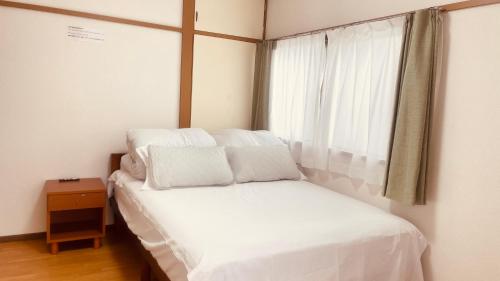a bedroom with a bed with white sheets and a window at Skytree Residence 錦糸町 駅から600M徒歩8分 in Tokyo