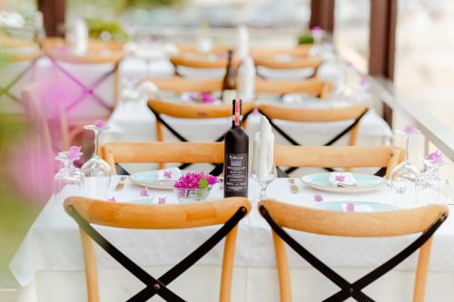ein langer weißer Tisch mit Stühlen und einer Flasche Wein in der Unterkunft Rea Boutique Hotel in Himarë