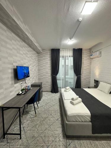 a bedroom with a bed and a desk and a tv at Beshchinor Hotel in Yakkasaray