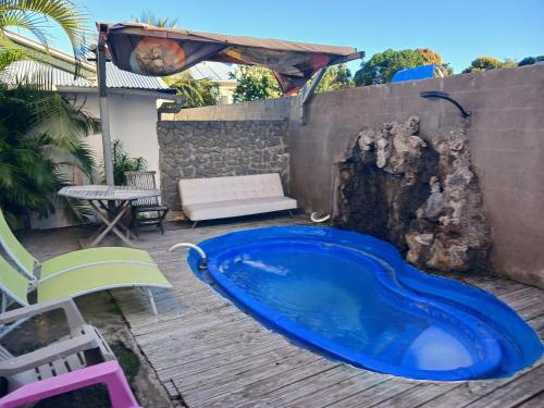 a blue swimming pool on a wooden deck at Villa du Nautique in Saint-Leu