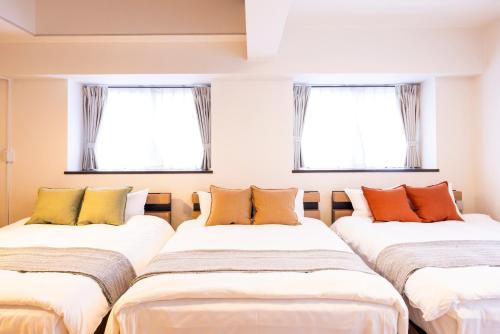three beds in a room with two windows at The Uchiyama Toko 博多 in Fukuoka