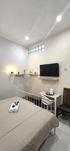 a bedroom with a bed and a desk and a tv at Ease Living Palem Kenari in Jatirarangan