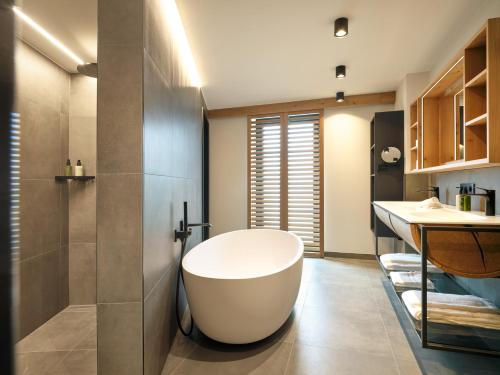 a bathroom with a white tub and a sink at Hotel Bütgenbacher Hof in Butgenbach