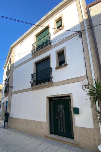 a white building with a green door and windows at Casa Turística Mareira O Grove in O Grove