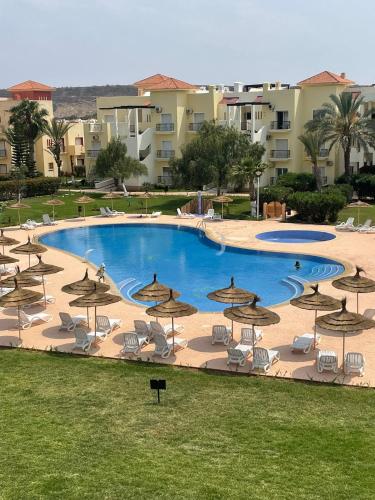 a large pool with chairs and umbrellas at Appartement résidence prive marina in Saidia 