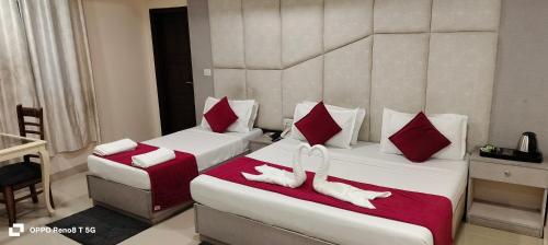 two beds in a hotel room with white towels on them at The Grand Paramont Near Delhi Airport Free Airport Drop in New Delhi