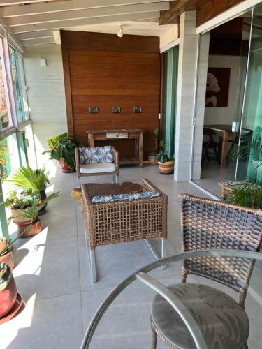 a porch with wicker chairs and a glass table at Pousada Bem Te Vi in Guarapari