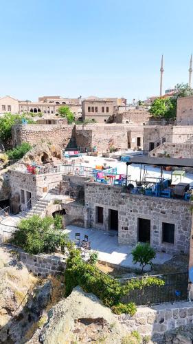 a stone building with tables and chairs on a hill at Kapadokya Ihlara Konakları Otel Konak Odaları in Guzelyurt