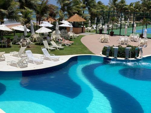 una piscina in un resort con sedie e ombrelloni di Genipabu Summer House Guarajuba a Camassari