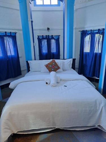 a bedroom with two beds with blue curtains at Dylan Cafe And Guest House in Jodhpur