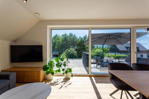 Una sala de estar con televisión, mesa y sillas. en Sunny Green Escape - Apartment with Terrace, en Lesce