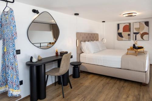 a bedroom with a bed and a desk and a mirror at Tinian Sunset Suite in Istérnia