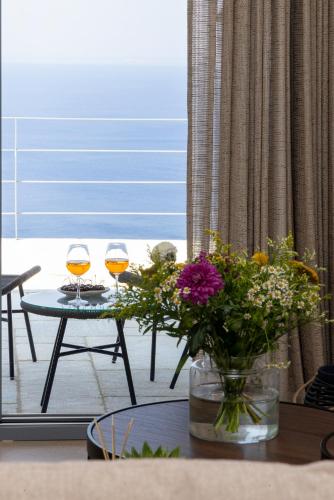 two glasses of wine sitting on a table with flowers at Tinian Sunset Suite in Istérnia