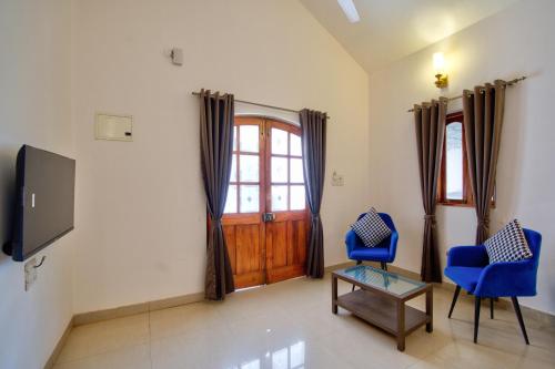 a living room with two blue chairs and a door at Close2C By The Arks Villa in Anjuna