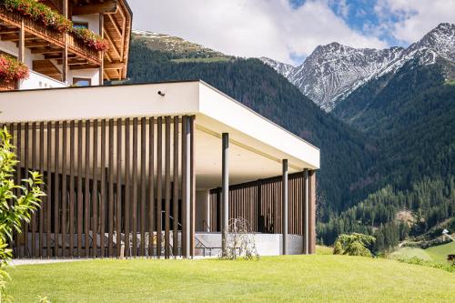 a building on a hill with mountains in the background at Mountain Residence Montana in Santa Maddalena in Casies