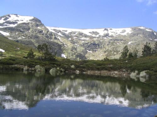 a mountain reflection in a lake with snow covered mountains at Hotel Punta me Torreblanca Palace in Guadarrama