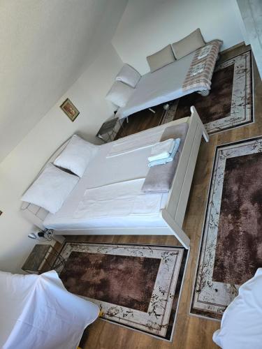 two beds in a room with white walls and wooden floors at Apartman Una Paradies in Bihać