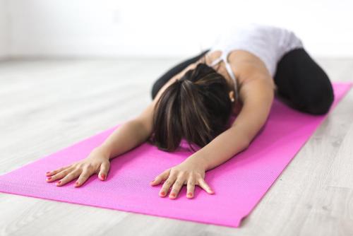 a young girl laying on a pink yoga mat at Alpin Family Resort Seetal in Kaltenbach