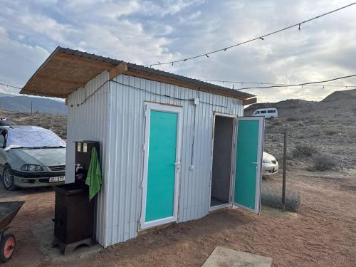 a small white shed with green doors in the desert at Crocodile Tash in Tong
