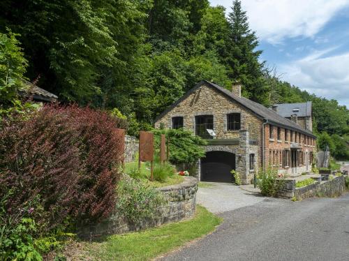 an old stone building with a garage on a road at La Pastorale in Manhay