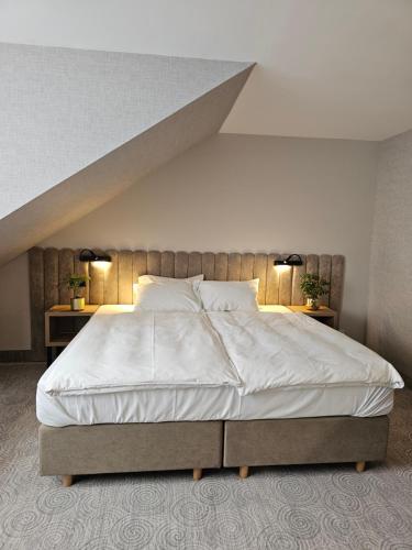 a bedroom with a large white bed with two lamps at Hotel Verde in Koszalin