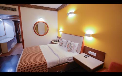 a hotel room with a bed and a mirror at Hotel Vrishali Executive in Kolhapur