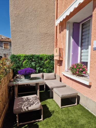 a small patio with a table and a bench and flowers at Chambre double l'escapade colorée in Rieux-Minervois