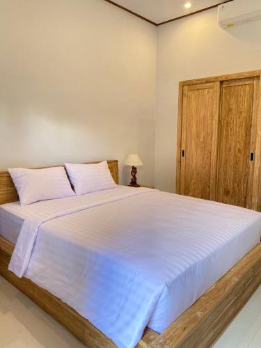 a bedroom with a large white bed with a wooden door at Uma Sari Amertha Homestay in Ubud