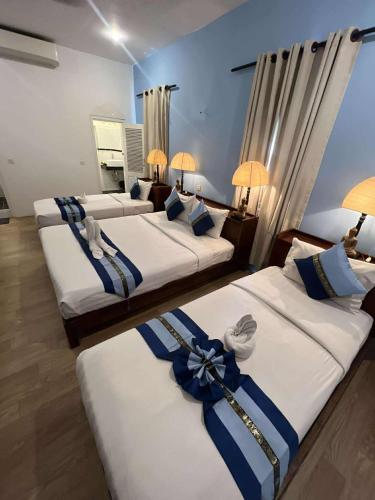 a room with three beds with blue bows on them at Pride Villa Cambodia in Phnom Penh