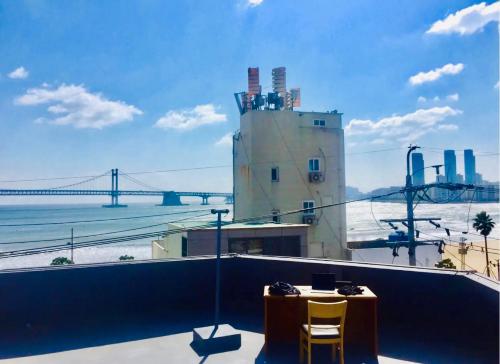 釜山Top Rated Cosy Gwangalli Room - 1 Min to Beach - Great Value的一座桥上的建筑物顶上有一张桌子和两把椅子