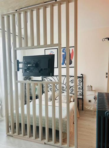 a bedroom with a crib with a television on it at Le nid des Petits à 15 min de Bordeaux in Sainte-Eulalie