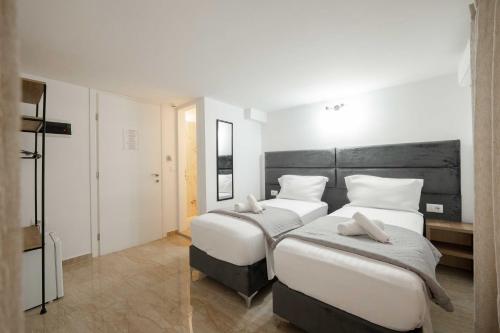 two beds in a room with white walls at Hotel Elite Sarande in Sarandë