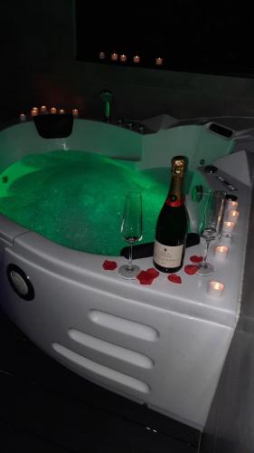 a hot tub with a bottle of wine and two glasses at La Bulle Armou 