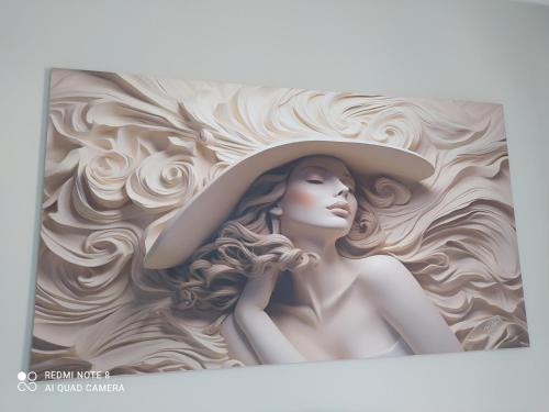 a painting of a woman wearing a hat on a wall at Hospedagem Altas da Quitéria Suíte 02 in Catas Altas