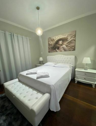 a bedroom with a white bed and a painting on the wall at Hospedagem Altas da Quitéria Suíte 02 in Catas Altas