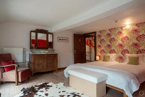 a bedroom with a large bed and a chair at La Pastorale in Manhay