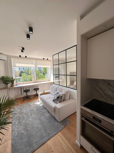 a living room with a white couch and a tv at Algirdo Sunlight Studio in Vilnius