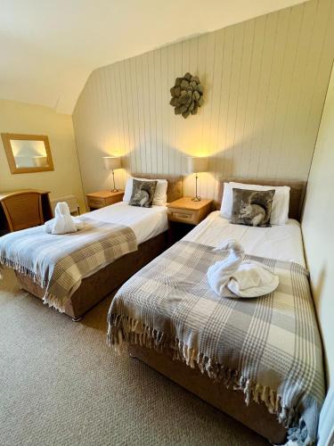 a hotel room with two beds with towels on them at Cottage Lea's Country Hotel & Restaurant in Pickering