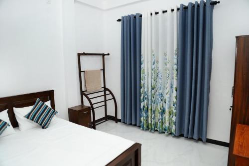 a bedroom with two beds and a blue curtain at Sandakini Home Rest in Ahangama