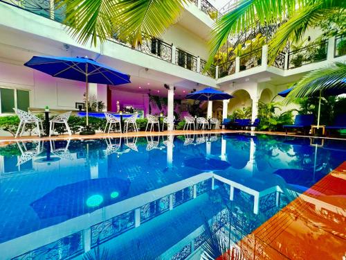a swimming pool with chairs and umbrellas in a building at Pride Villa Cambodia in Phnom Penh