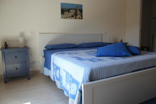 una camera da letto con letto con lenzuola blu e comodino di Amaca Iblea a Ragusa