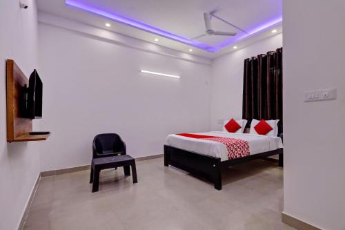 Un dormitorio con una cama y una silla negra. en Hotel O Maruthi Paradise Netaji Udyanavana Park, en Bangalore