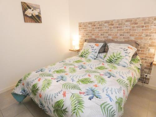 a bed with a white comforter with palm leaves at L'etable in Orx