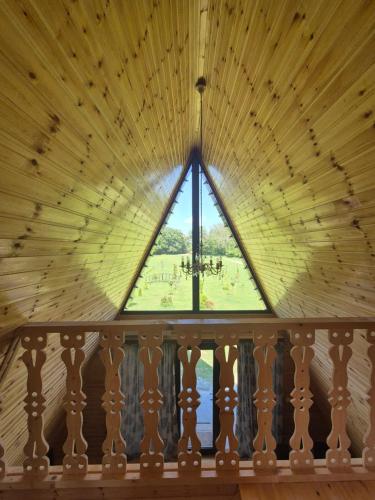 a window in a wooden ceiling with a view of a park at Rancho Didostati in Dzveli Abasha
