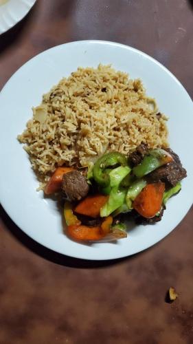 a white plate of food with rice and meat at Ultar House in Karimabad Hunza