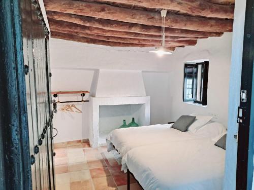 a white bedroom with two beds and a fireplace at Alquería de Tajarja in Tajarja