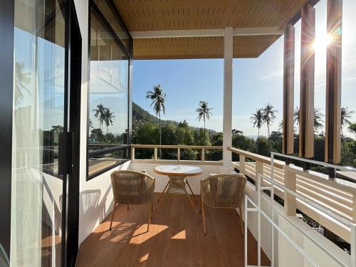 a balcony with a table and chairs and palm trees at Field-D House in Koh Tao