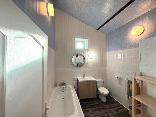 a bathroom with a tub and a toilet and a sink at Maison Zen 2 chambres - Touverac in Touvérac