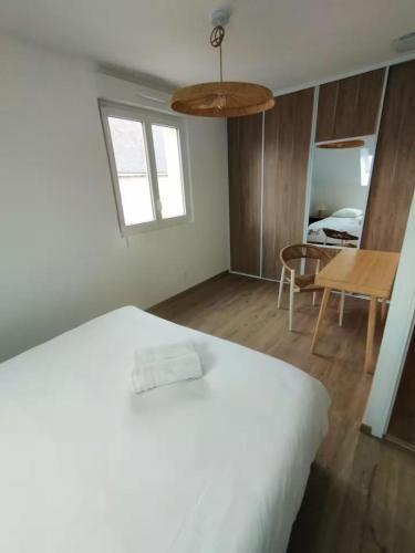 a bedroom with a white bed and a table at La Grange - Maison et Parking - Portes de Chartres in Jouy