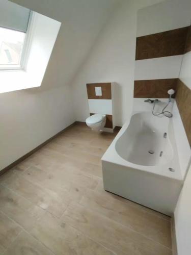 a bathroom with a white tub and a toilet at La Grange - Maison et Parking - Portes de Chartres in Jouy